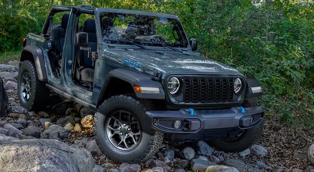 A grey 2024 Jeep Wrangler Willys is off-roading on a rocky trail.