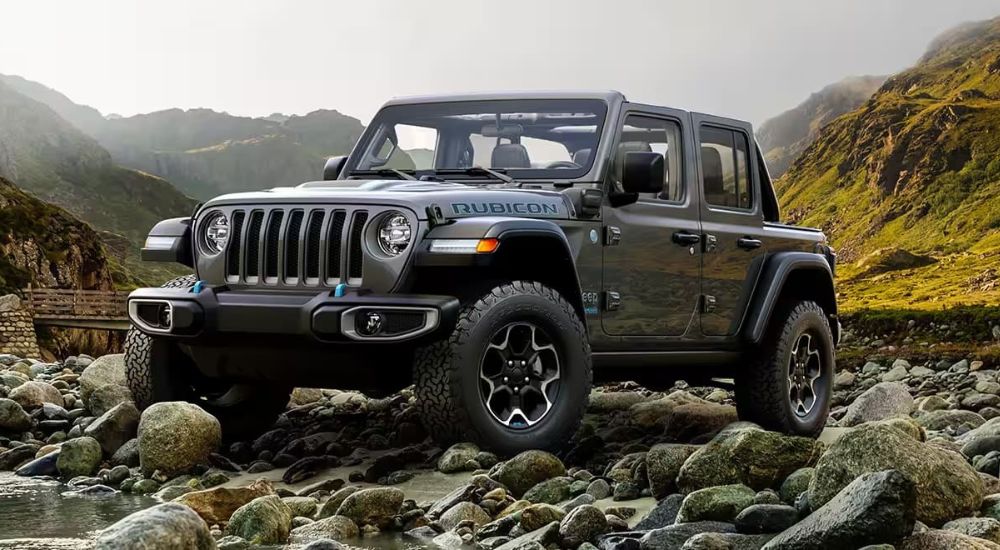 A popular Jeep Wrangler for sale, a grey 2024 Jeep Wrangler 4xe Rubicon, is shown parked on rocks.